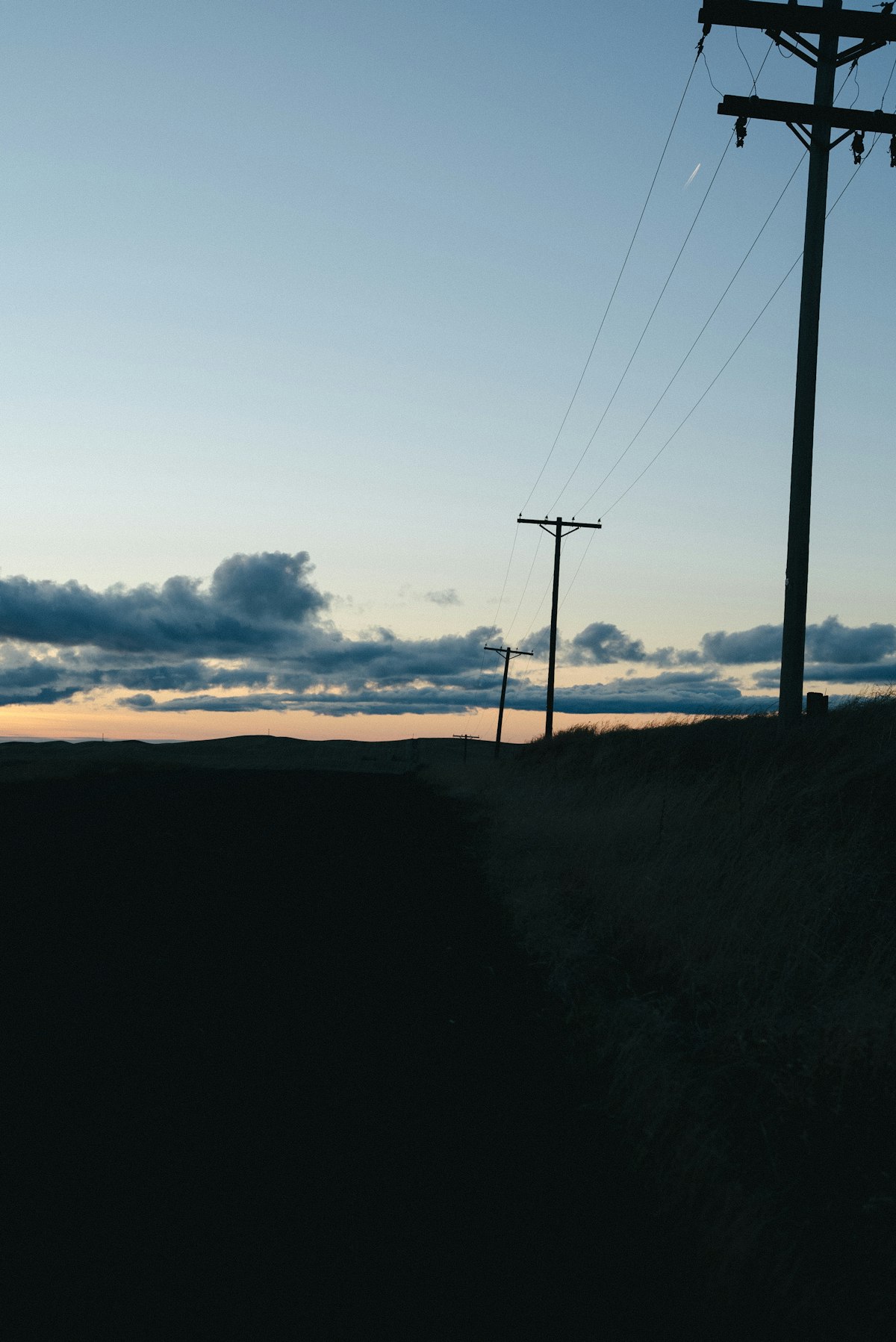 Postes de alta tensão ao pôr do sol — uma infraestrutura desenhada para o século XX que não consegue escoar a energia limpa do século XXI