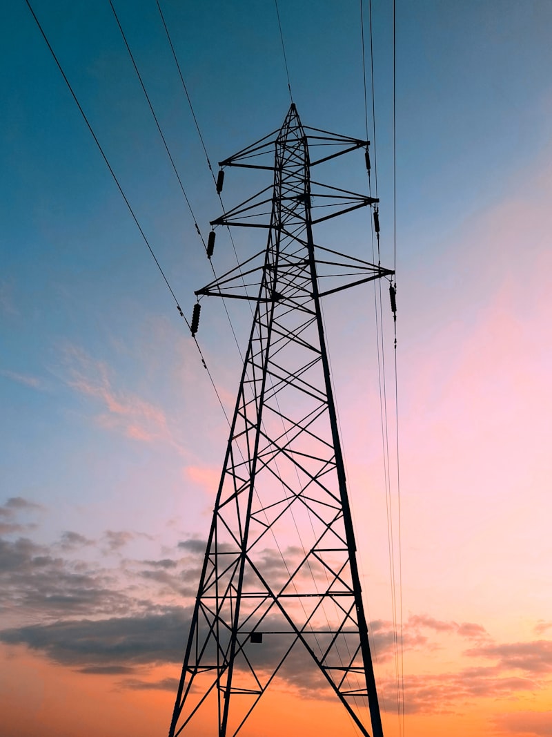 Poste de alta tensão ao pôr do sol — a modernização da rede elétrica europeia pode custar biliões