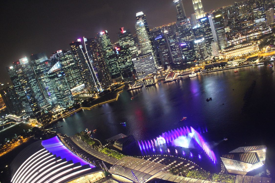 Vista noturna da Marina Bay, em Singapura, com o skyline do CBD e o show de luzes Spectra, representando uma smart city altamente conectada por redes 5G