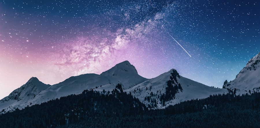 Céu noturno com a Via Láctea sobre montanhas cobertas de neve.