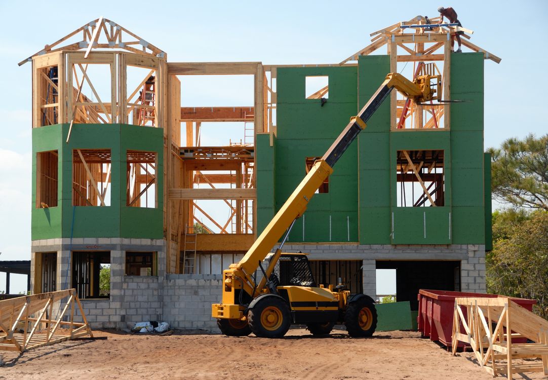 Estaleiro de obras com blocos de betão e estrutura de madeira durante construção de habitação