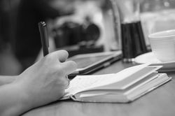Mão a escrever com caneta num caderno