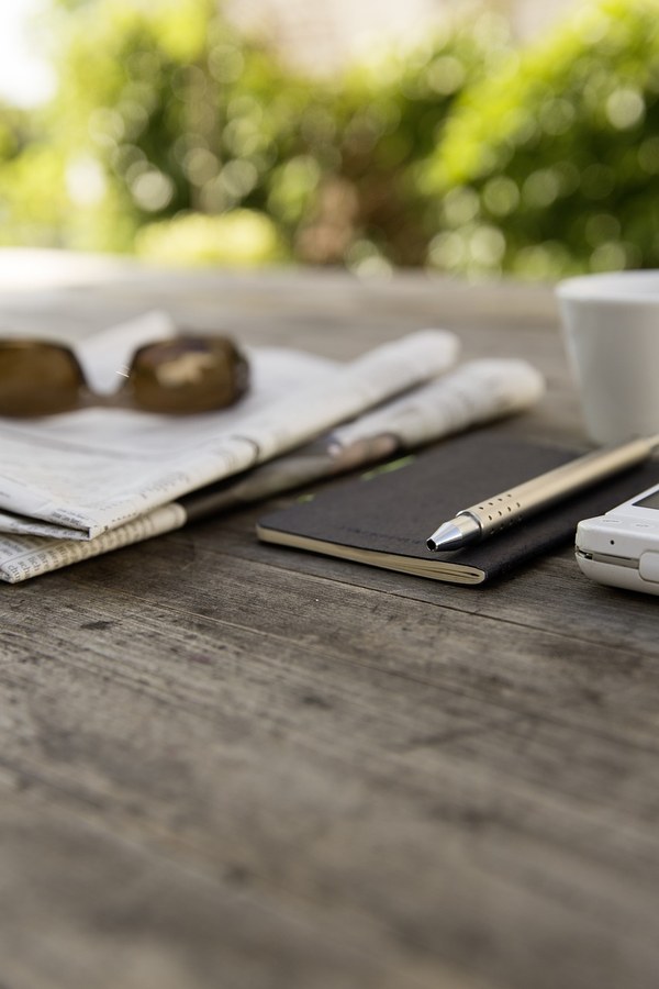 Jornal e smartphone sobre uma mesa rústica