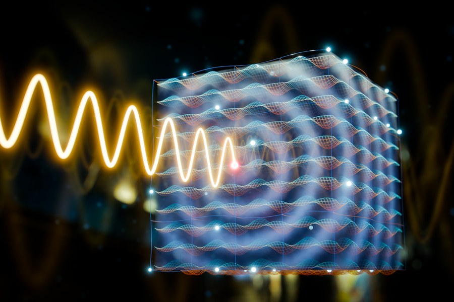 Ilustração do HZDR: uma onda terahertz (dourada) a interagir com um cristal de tempo fotónico — uma estrutura cúbica com grelha de ondas azuis e laranjas