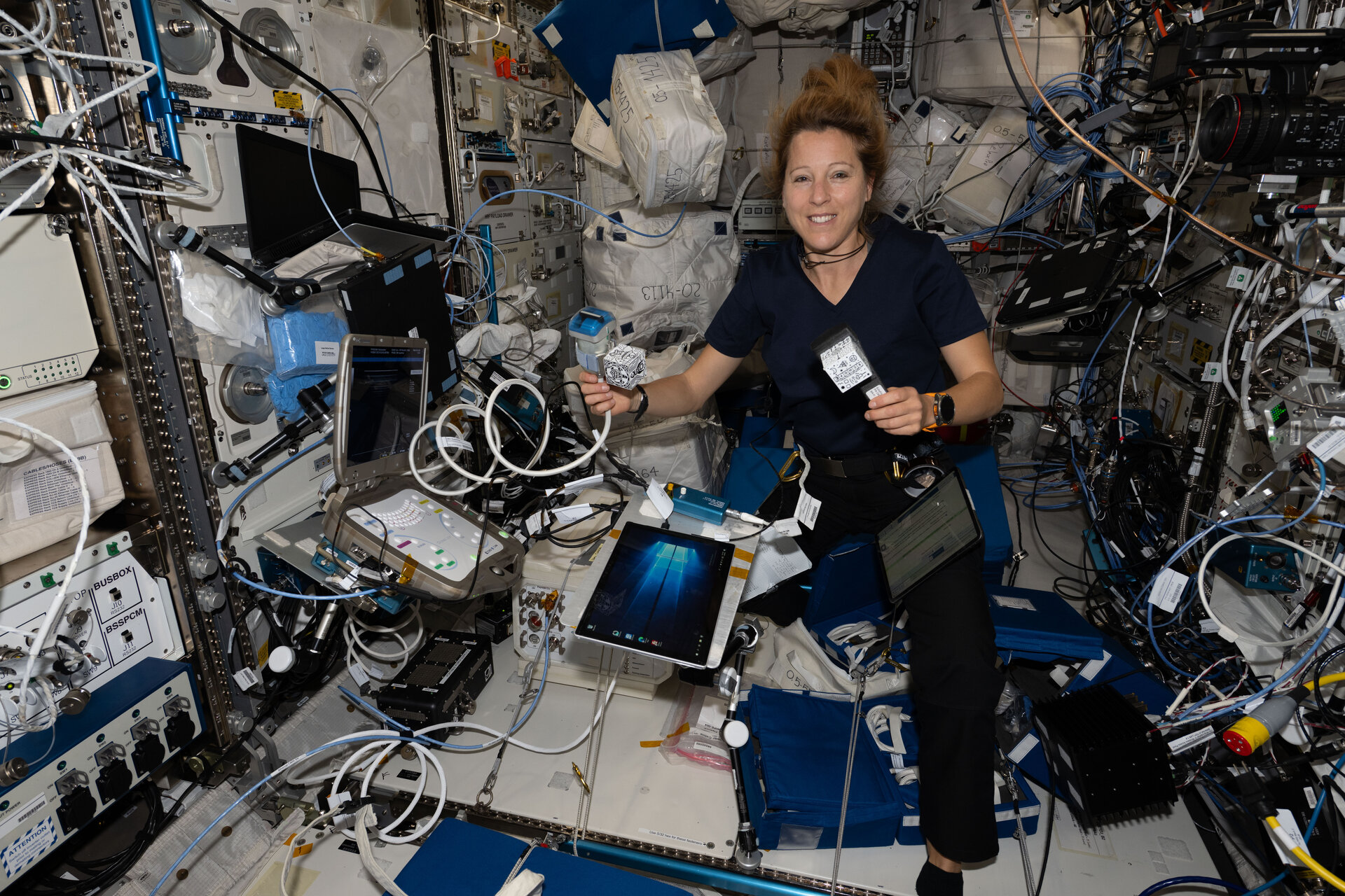 A astronauta Sophie Adenot prepara uma sessão EchoFinder no interior da Estação Espacial Internacional, com equipamento de ecografia e uma tableta visíveis.