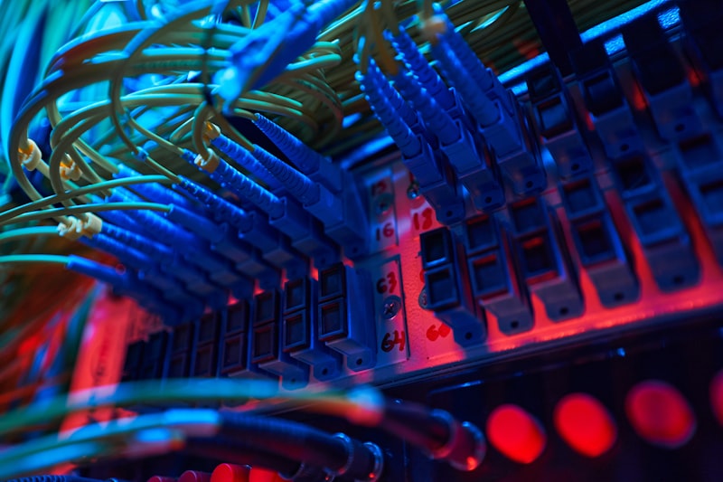 Cabos de fibra ótica azuis ligados a um painel de switch, representando a infraestrutura de rede que os atacantes exploraram no FortiBleed