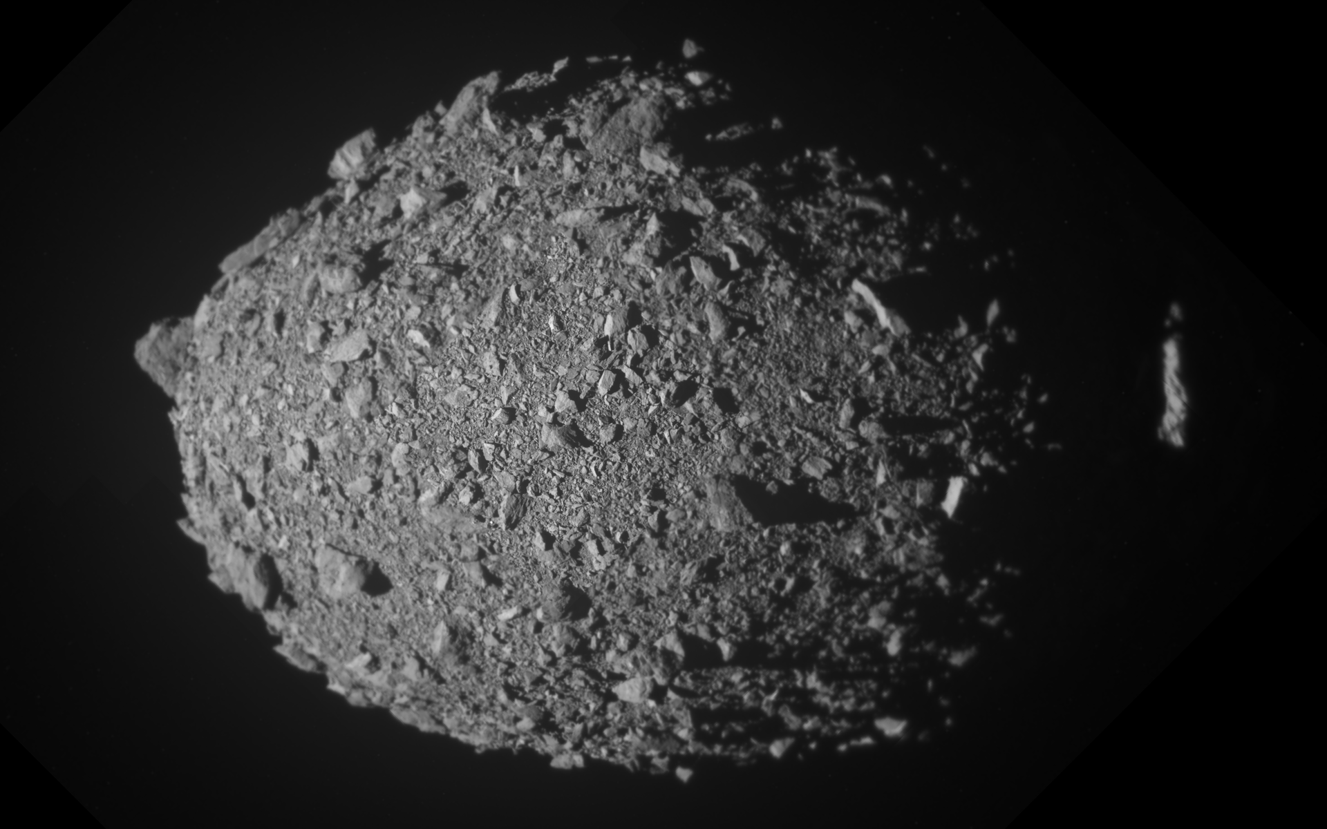 O asteroide Dimorphos em tons de cinzento sobre fundo preto: um corpo irregular coberto de blocos e pedras soltas de várias dimensões.