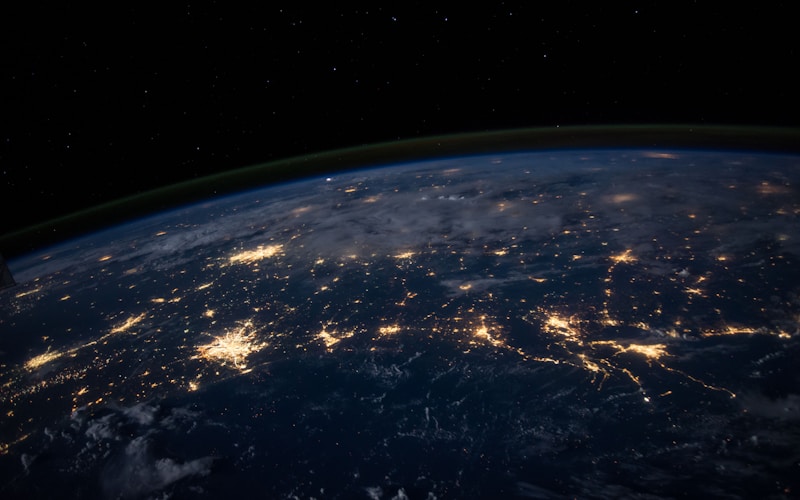 Terra vista do espaço à noite com as luzes das cidades acesas — a conectividade global que os cabos submarinos como o PISCES tornam possível entre continentes.