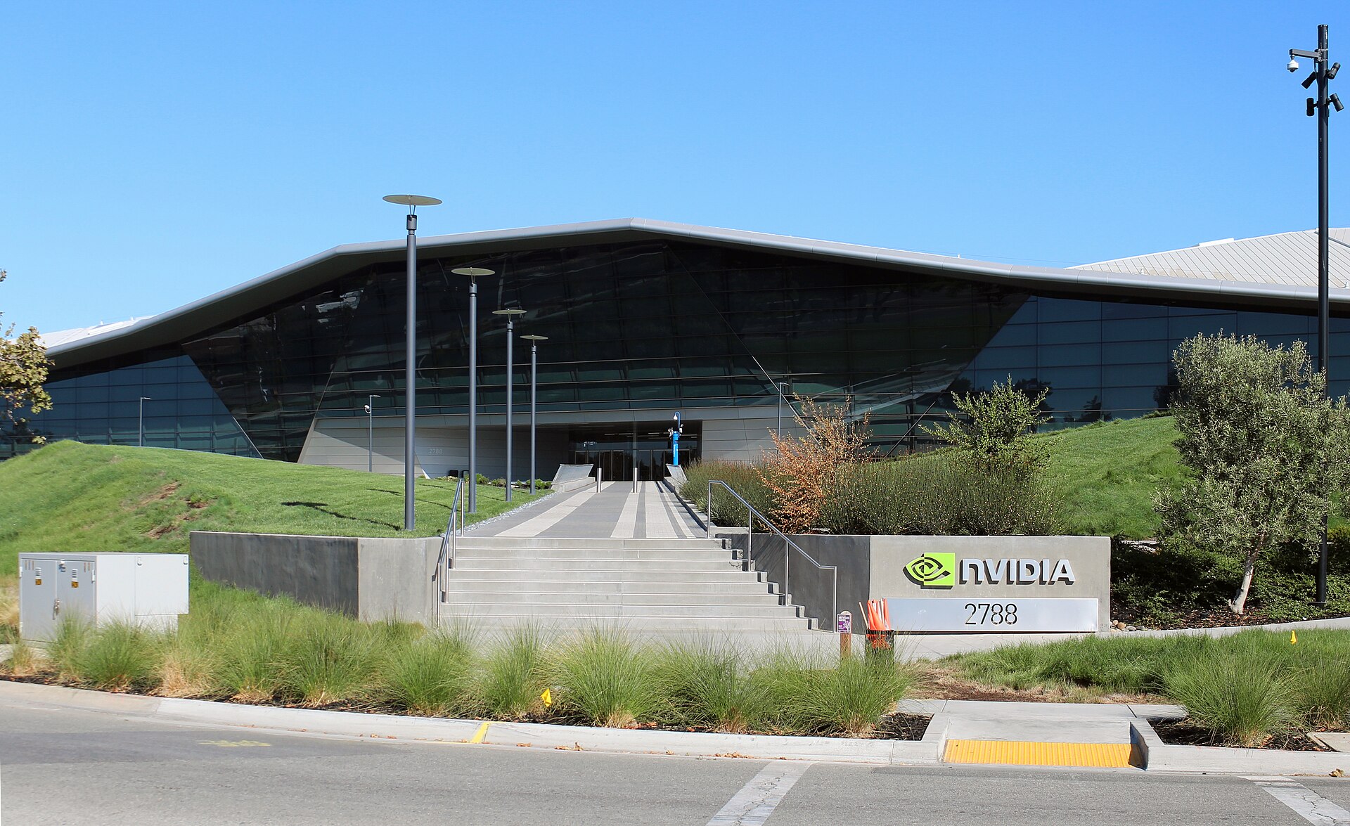 Fachada de vidro da sede da Nvidia em Santa Clara, vista da rua, com escadas largas de acesso e um painel junto à relva onde se lê Nvidia e o número 2788