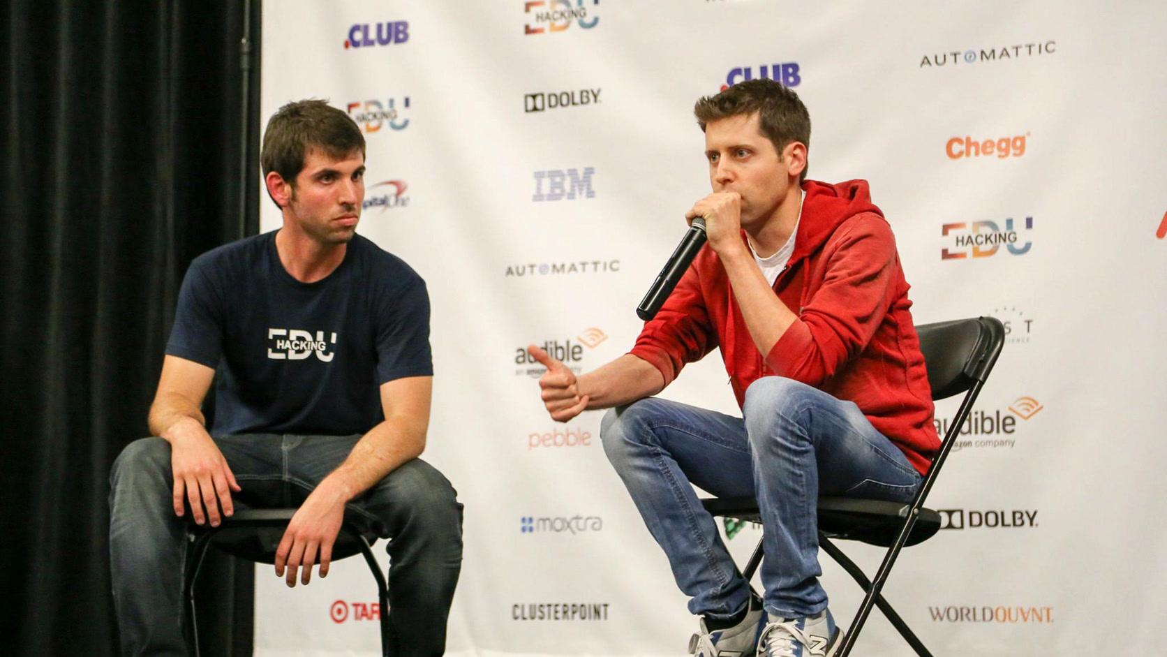 Sam Altman sentado frente ao entrevistador num fireside chat do HackingEDU