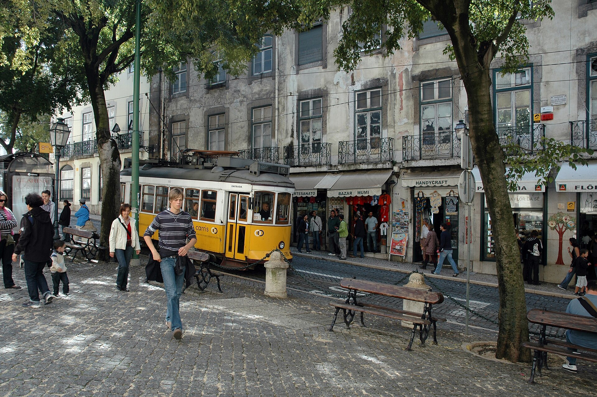 Elétrico amarelo da Carris, número 582, numa rua comercial da zona da Sé, em Lisboa; fotografia de arquivo de 2010, não do veículo mostrado no vídeo da OpenAI.