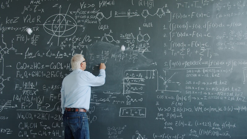 Professor com cabelo branco escrevendo equações complexas num quadro negro repleto de fórmulas de cálculo, física e química — a imagem do conhecimento humano que a IA começa a replicar