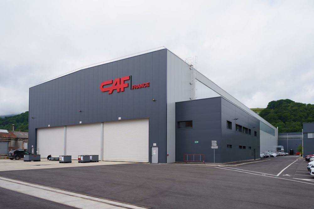 Edifício da CAF France com instalações fabris e portas de acesso para material ferroviário