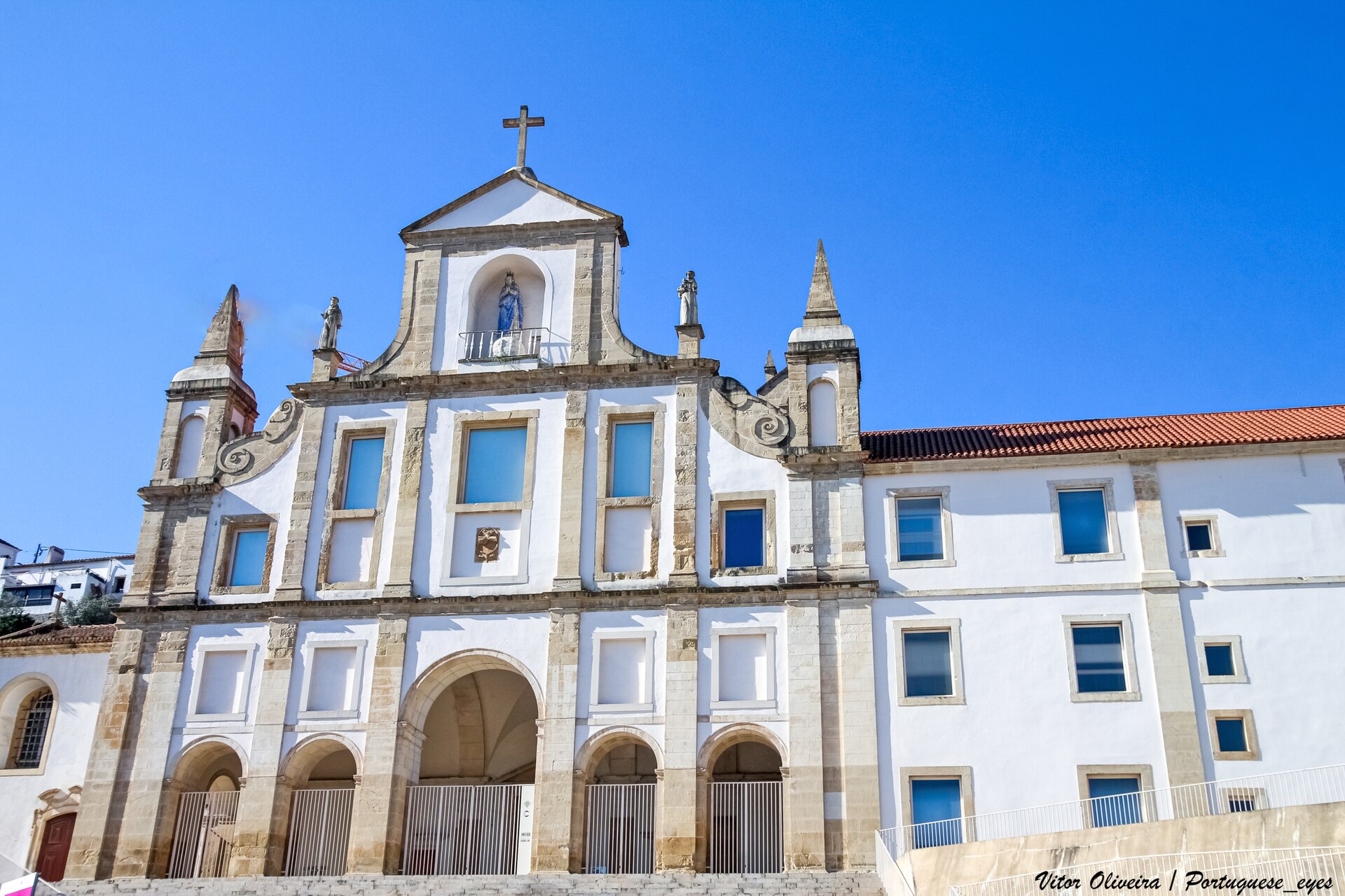 Fachada branca e de pedra do Convento São Francisco, em Coimbra, sob céu azul.