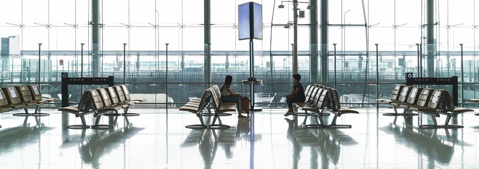 Interior amplo de um terminal aeroportuário com passageiros sentados numa zona de espera