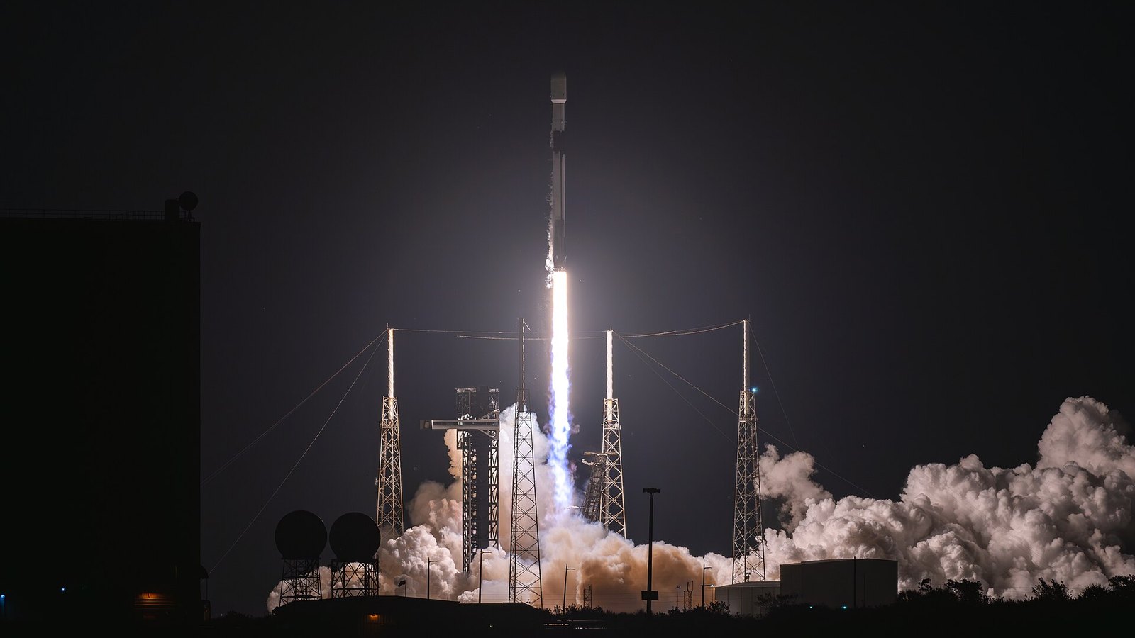 Foguetão Falcon 9 a descolar de noite do complexo de lançamento 40, em Cabo Canaveral, com a coluna de fumo iluminada pelos motores