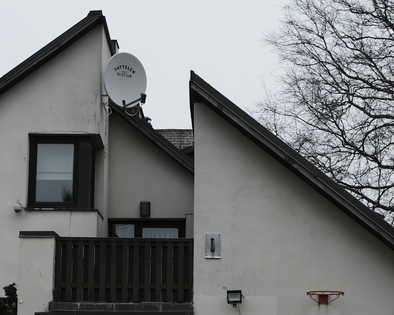 Casa branca com antena parabólica no telhado contra um céu nublado — a imagem da conectividade rural que a Starlink veio transformar