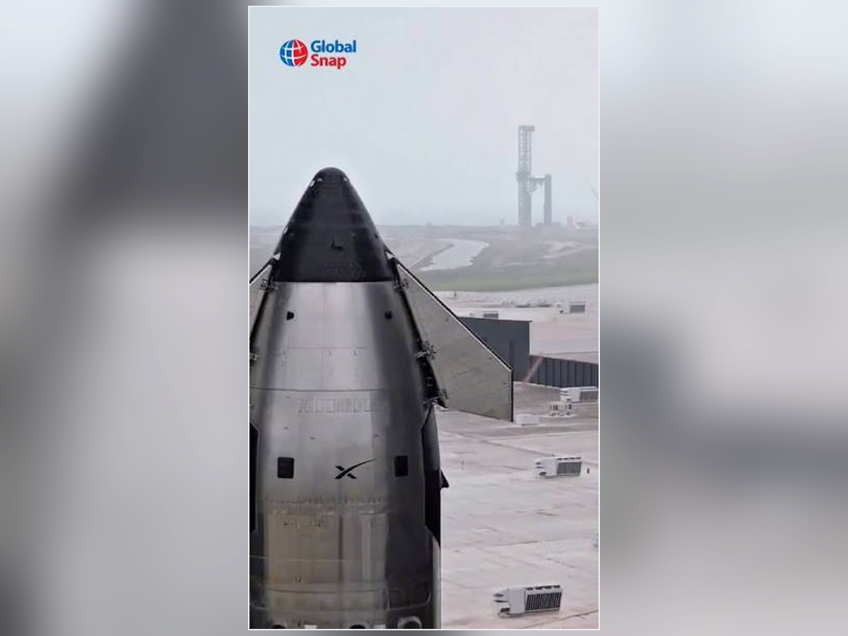 Starship no solo, com uma estrutura elevada e instalações ao fundo; a marca Global Snap está visível.