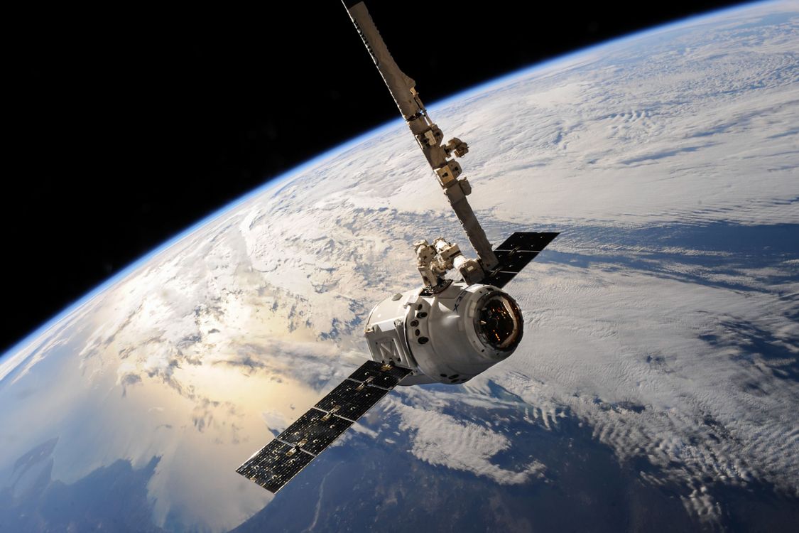Cápsula espacial SpaceX Dragon capturada pelo braço robótico Canadarm2 da Estação Espacial Internacional — a exploração espacial continua a expandir os limites do conhecimento humano