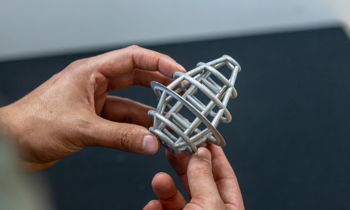 Peça de treliça de titânio impressa em 3D segurada pelas mãos de um investigador