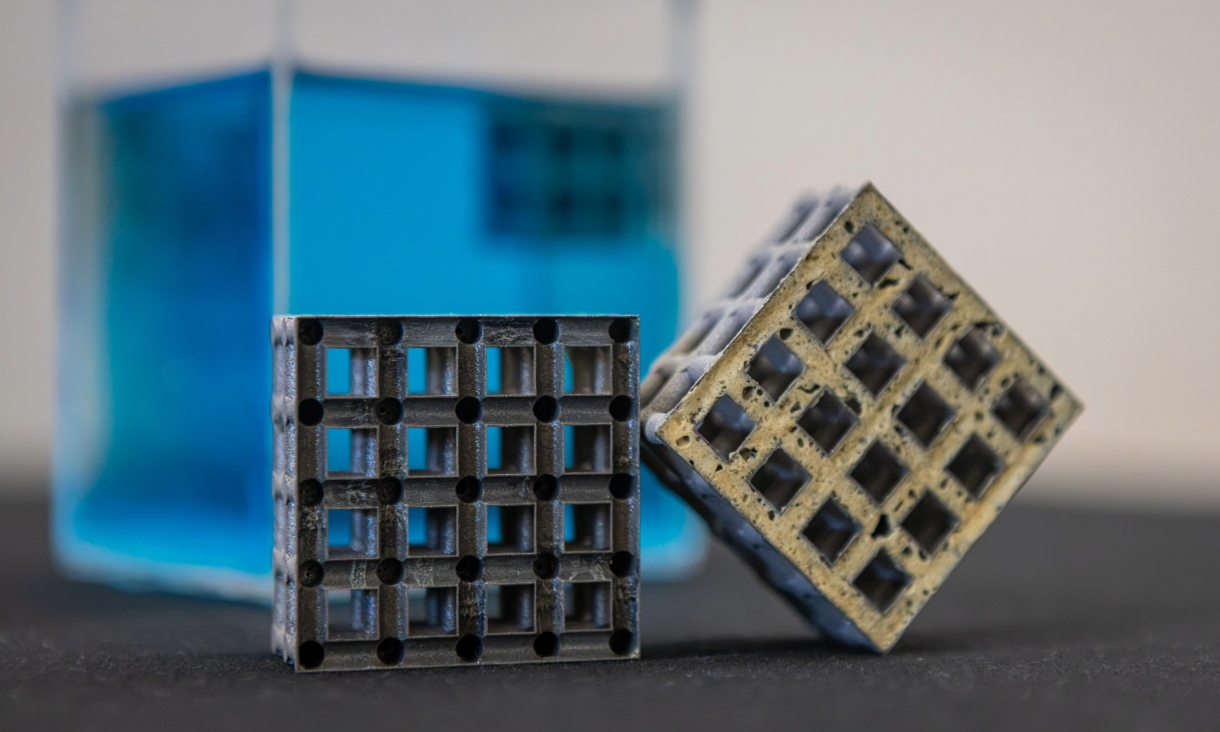 Duas secções de treliças metálicas impressas em 3D junto a um tanque de água