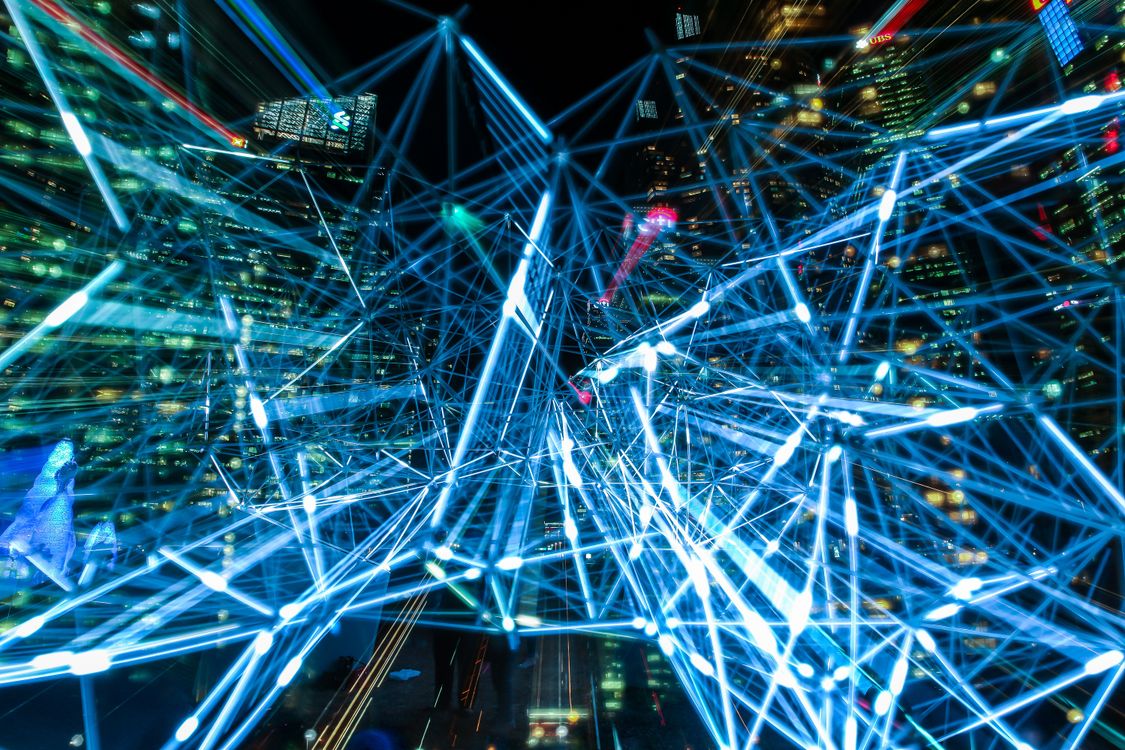 Instalação artística de luz com linhas azuis interligadas, representando visualmente a conectividade digital e as emissões eletromagnéticas que transportam dados no ar.