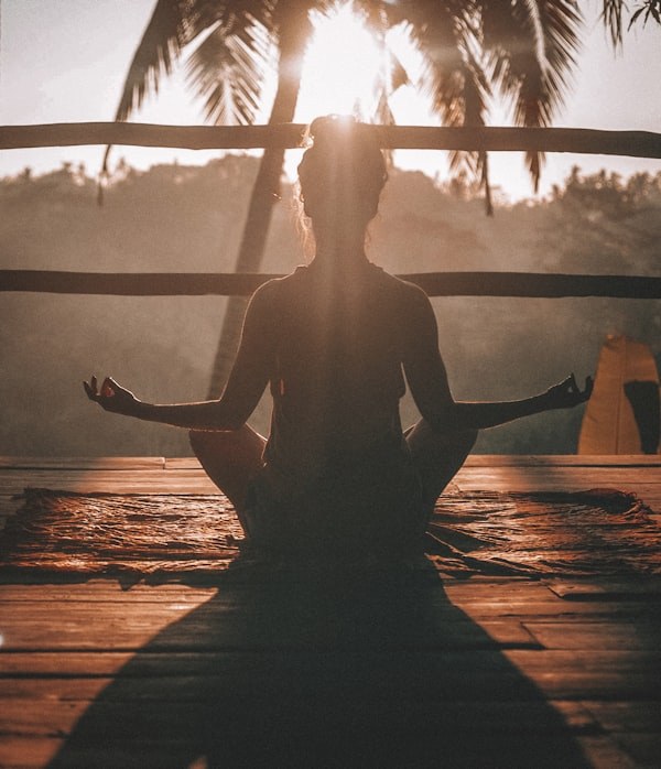 Pessoa a meditar ao ar livre ao nascer do sol — recuperação e bem-estar