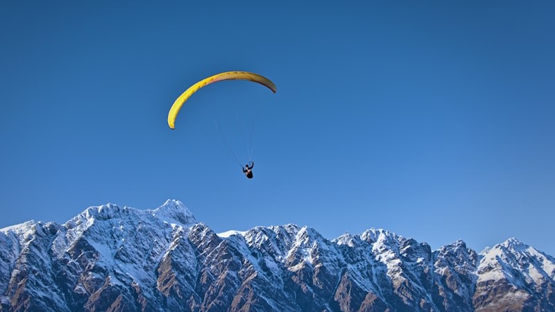Parapente a voar contra o céu azul dos Alpes